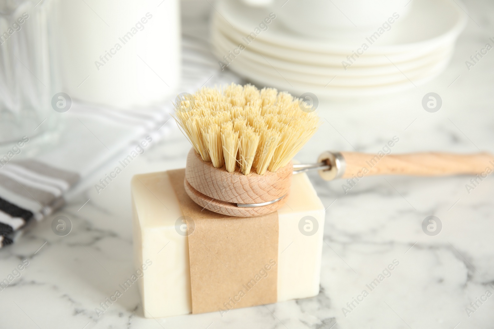 Photo of Cleaning brush and soap bar for dish washing on white marble table indoors, closeup