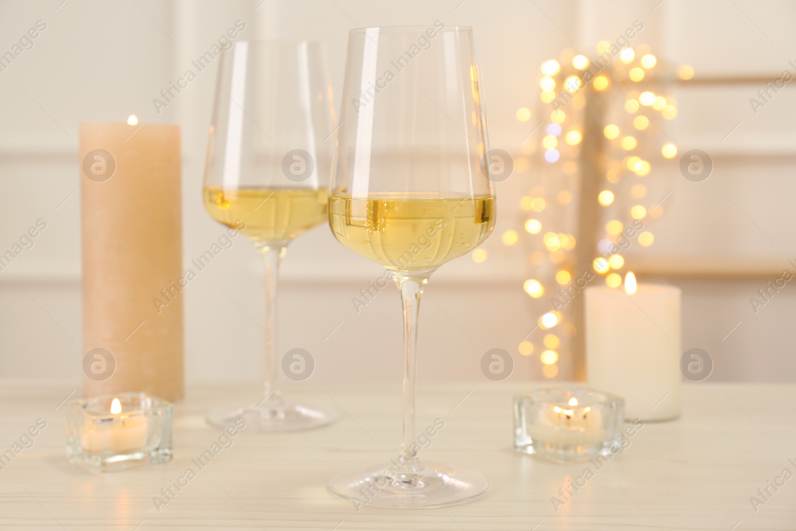Photo of Glasses of wine and candles on wooden table
