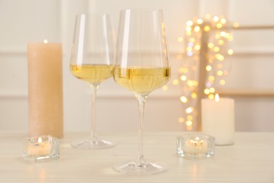 Glasses of wine and candles on wooden table