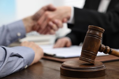 Photo of Lawyer shaking hands with client in office, focus on gavel