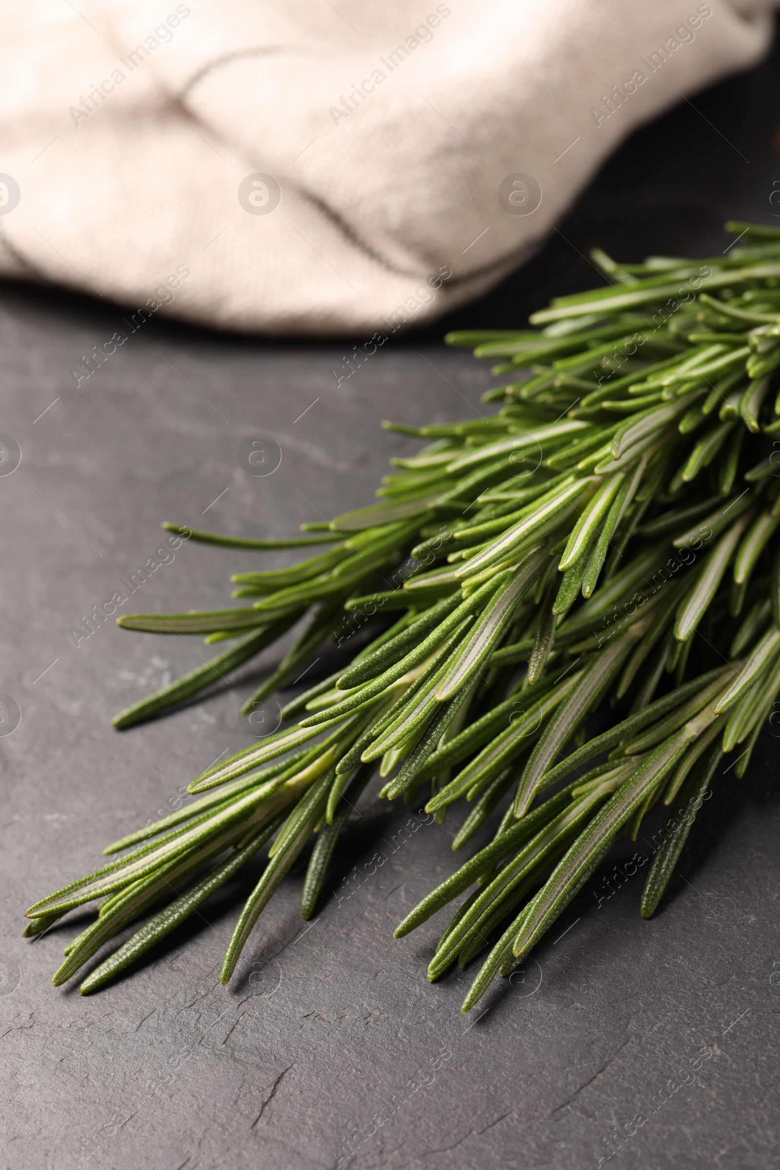 Photo of Bunch of fresh green rosemary on dark grey table, closeup