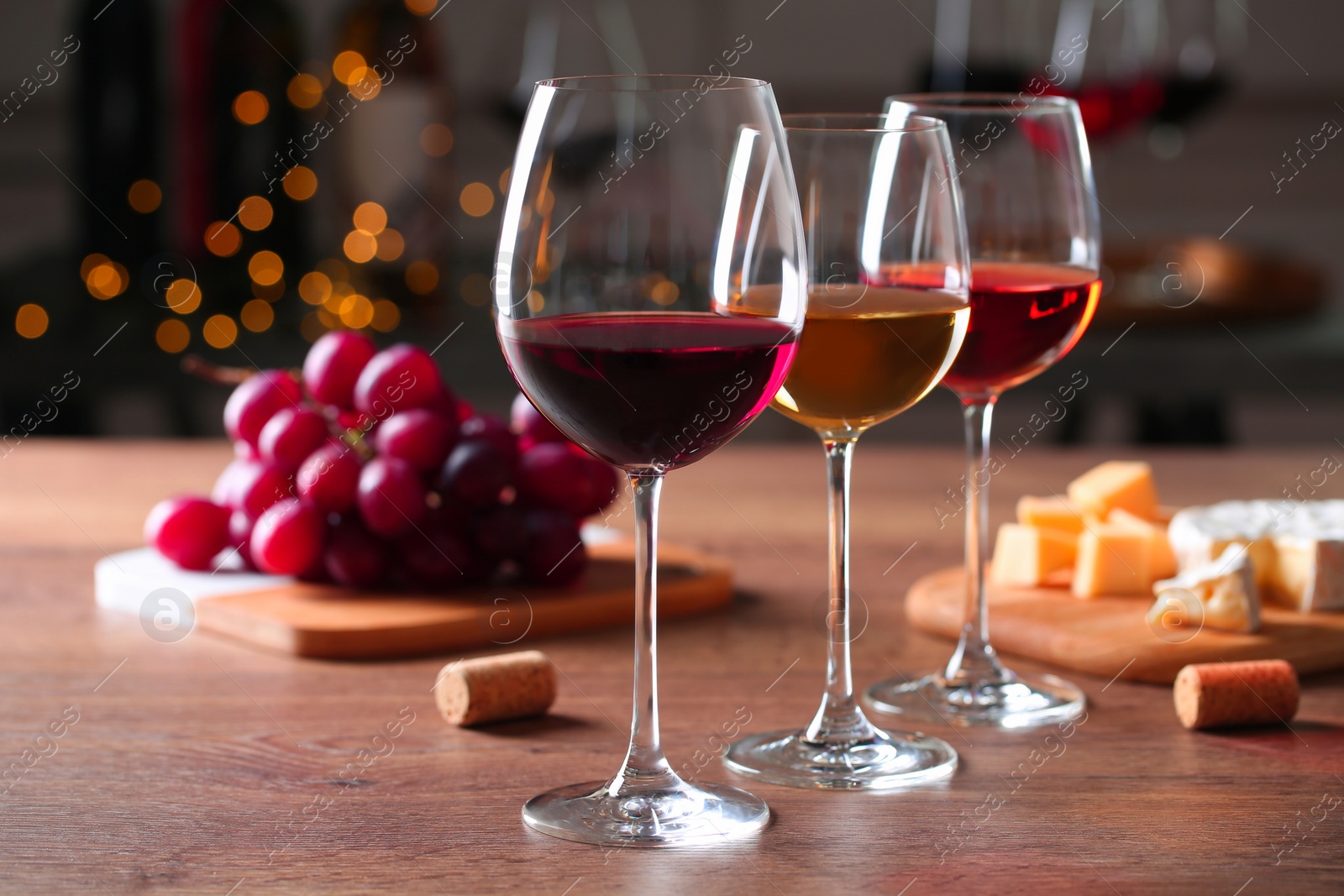 Photo of Glasses with different wines and appetizers on wooden table against blurred background. Space for text