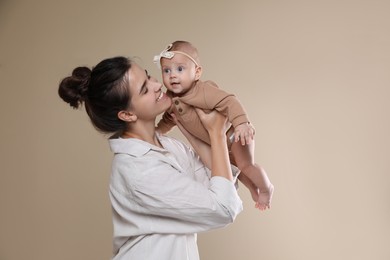 Beautiful mother with her cute baby on beige background