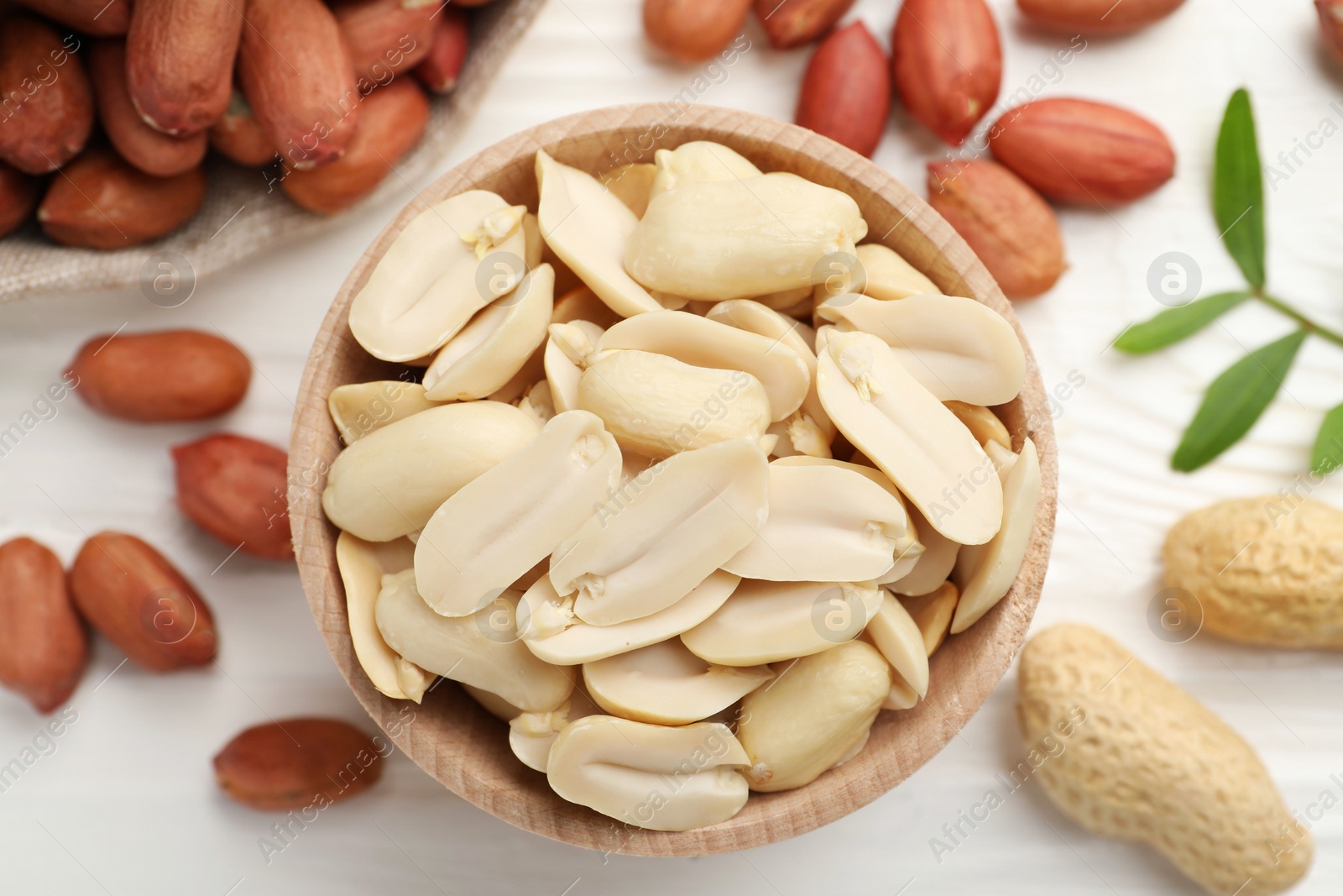 Photo of Fresh peanuts and twig on white wooden table, flat lay