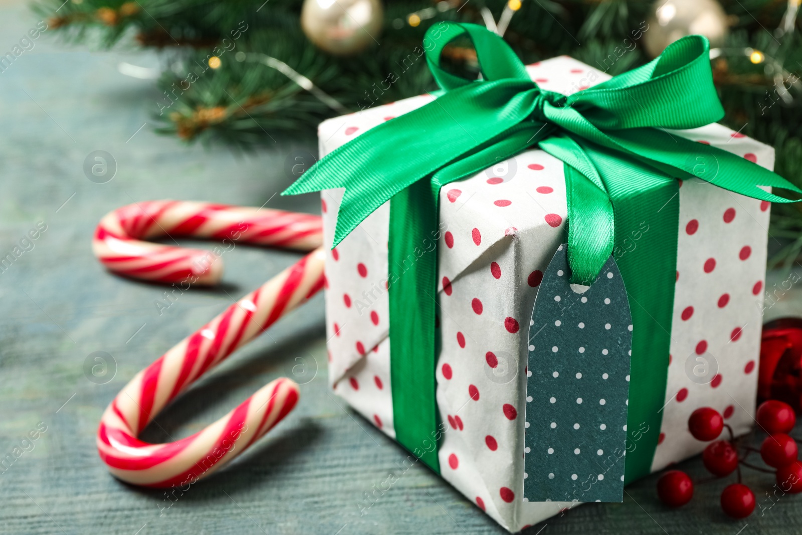 Photo of Christmas gift box, candy canes and festive decor on blue wooden table. Space for text