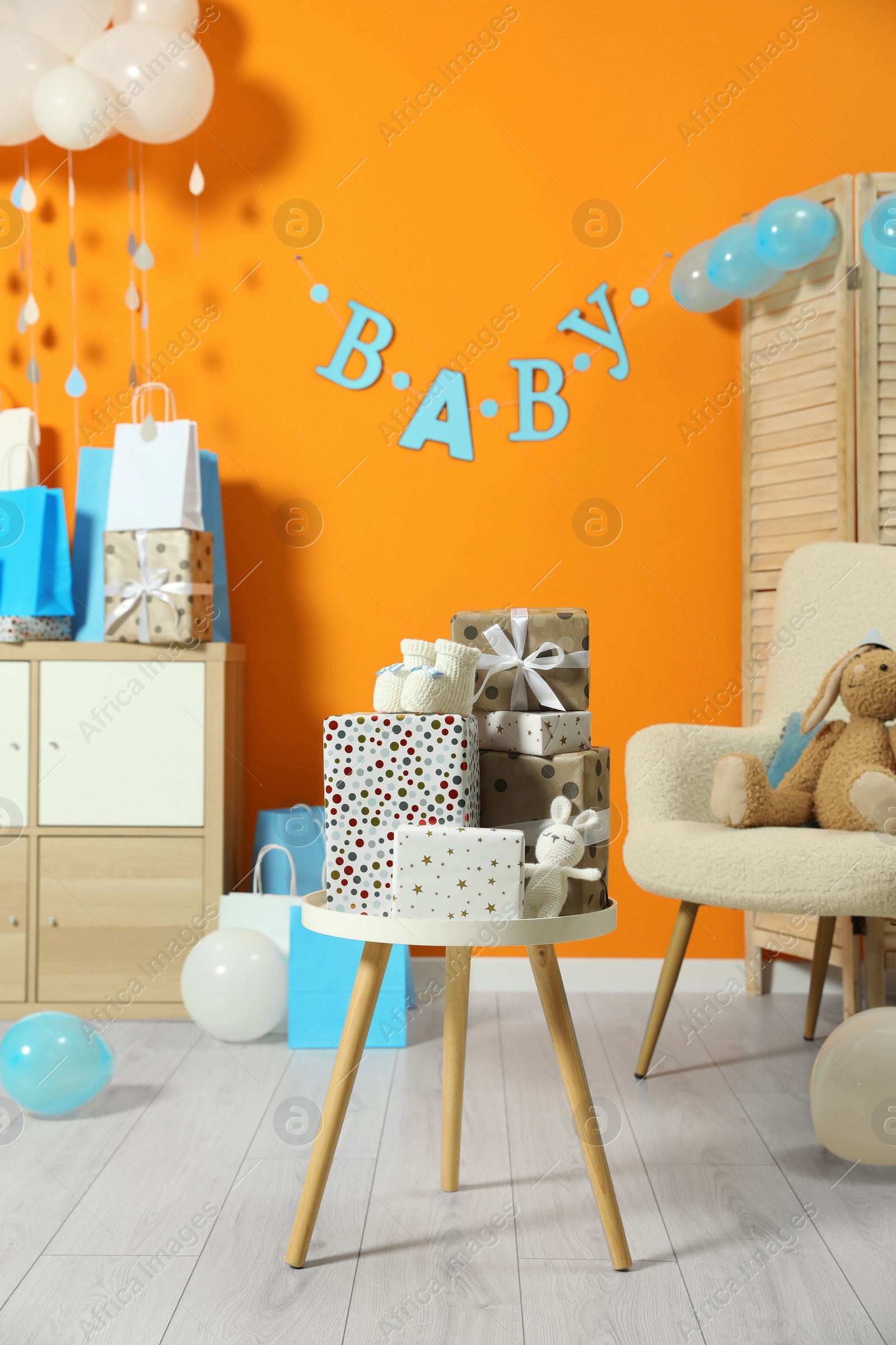 Photo of Baby shower party. Festive decor, gift boxes, booties and toys in stylish room