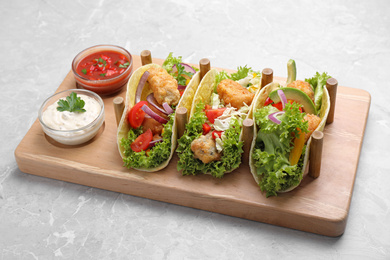 Photo of Delicious fish tacos served on grey marble table