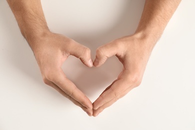 Photo of Man making heart with his hands on white background, top view