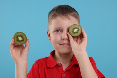 Photo of Boy with fresh kiwi on light blue background