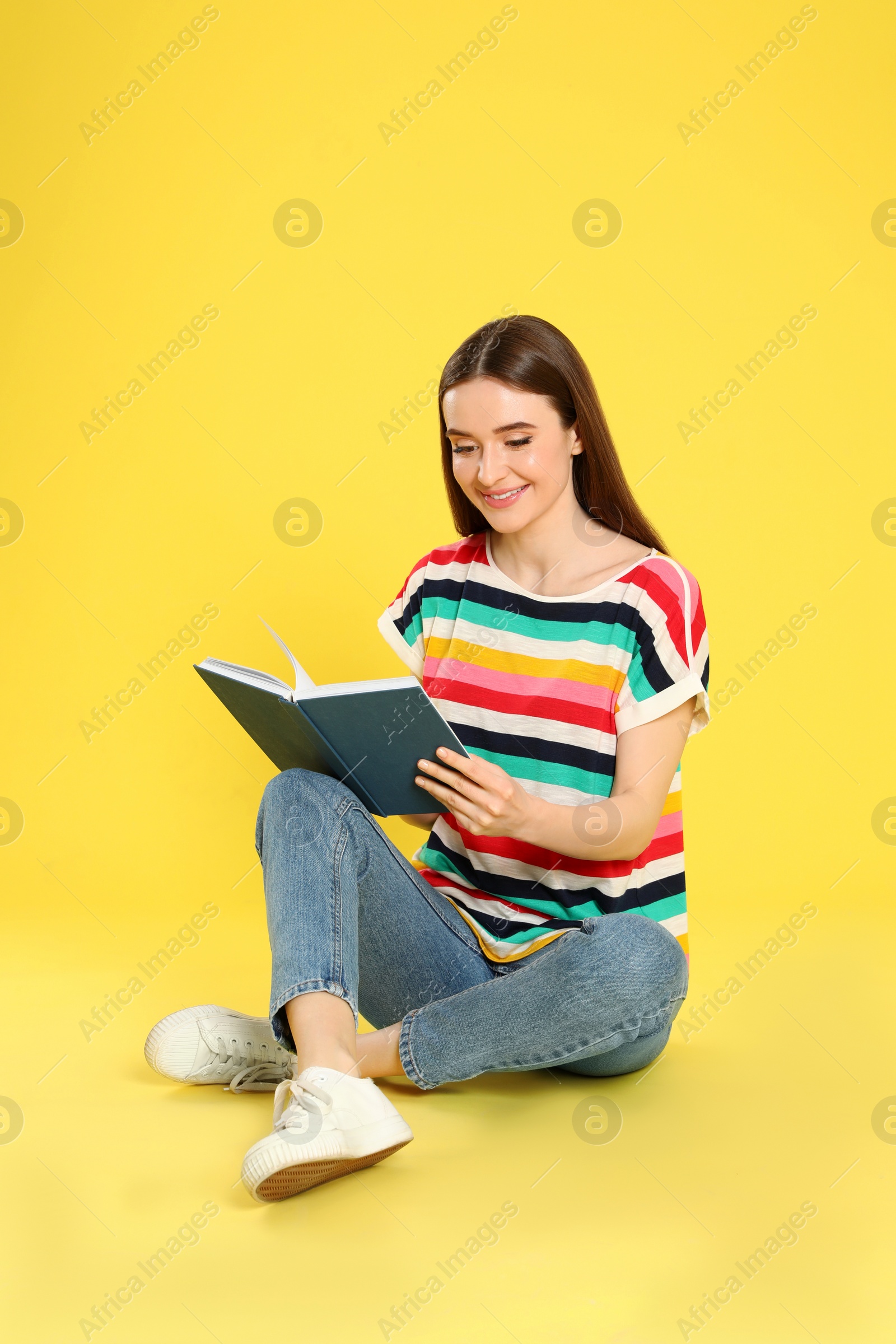 Photo of Young woman reading book on color background, space for text