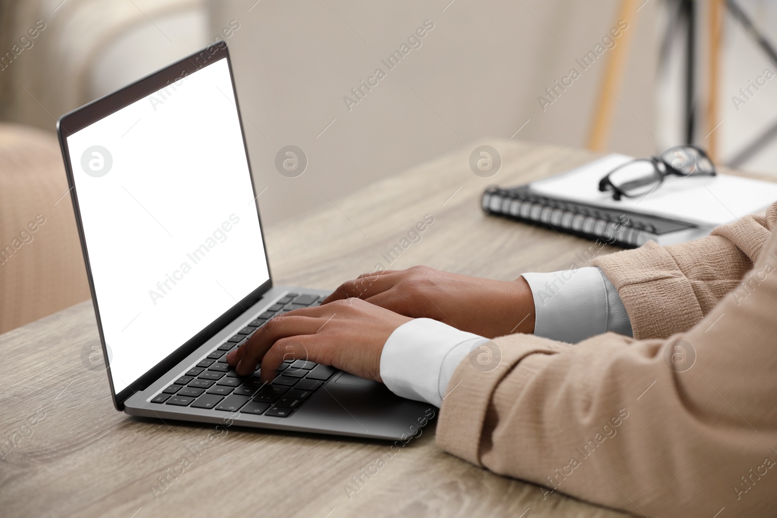 Photo of Woman using laptop at wooden desk indoors, closeup