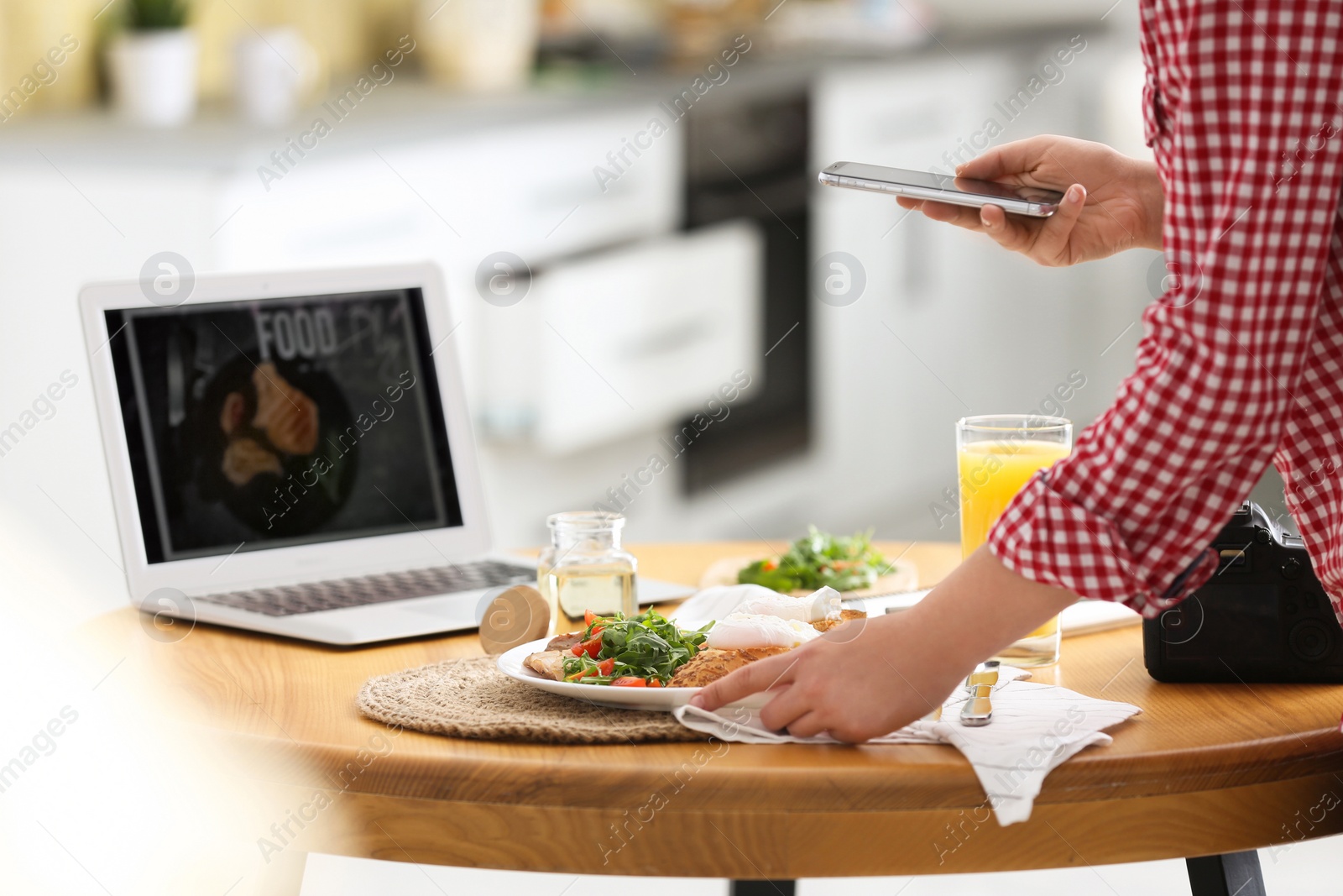 Photo of Food blogger taking photo of her lunch at wooden table indoors, closeup