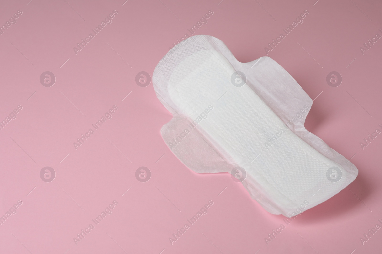 Photo of Sanitary napkin on pink background, space for text