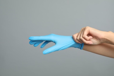 Photo of Doctor wearing medical gloves on grey background, closeup