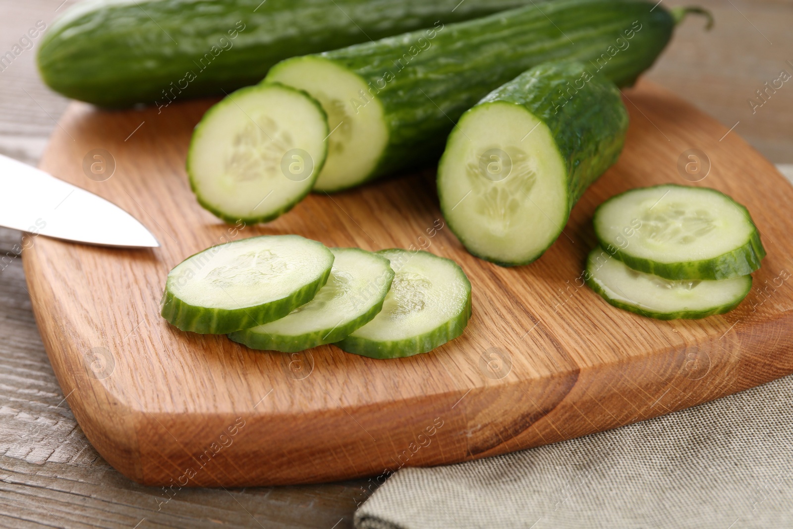 Photo of Cucumbers. knife and cutting board on table, closeup