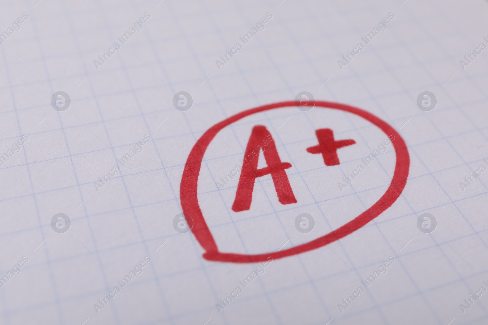 Photo of School grade. Red letter A with plus symbol on notebook paper, closeup