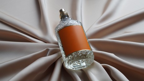 Photo of Luxury bottle of perfume on beige silk