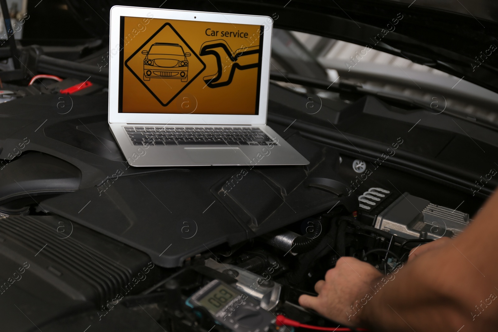 Photo of Mechanic with laptop doing car diagnostic at automobile repair shop, closeup