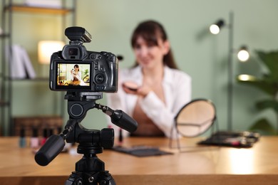 Photo of Beauty blogger recording makeup tutorial at home, focus on camera