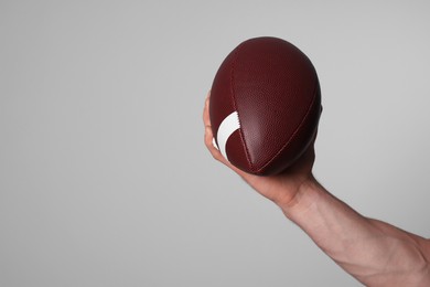 Photo of Man with American football ball on light grey background, closeup. Space for text