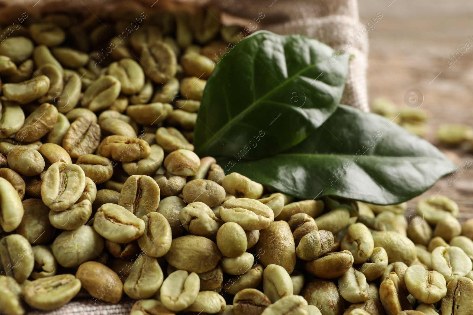 Photo of Green coffee beans and leaves on table, closeup
