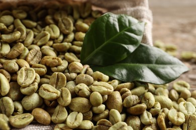 Green coffee beans and leaves on table, closeup