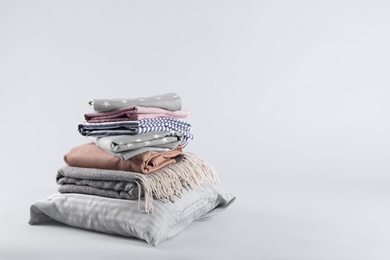 Photo of Stack of clean bed sheets and pillow on white background. Space for text