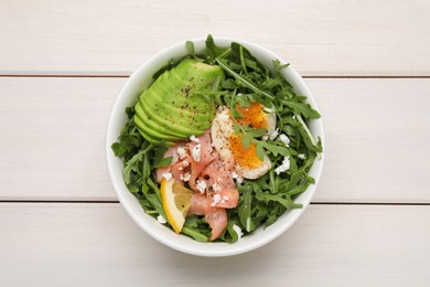 Photo of Delicious salad with boiled egg, salmon and avocado in bowl on white wooden table, top view