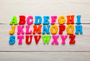 Photo of Colorful magnetic letters on white wooden table, flat lay. Alphabetical order