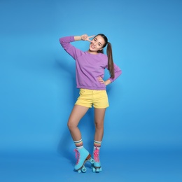 Full length portrait of young woman with roller skates on color background