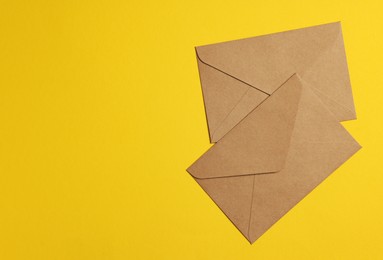 Envelopes made of parchment paper on yellow background, flat lay. Space for text