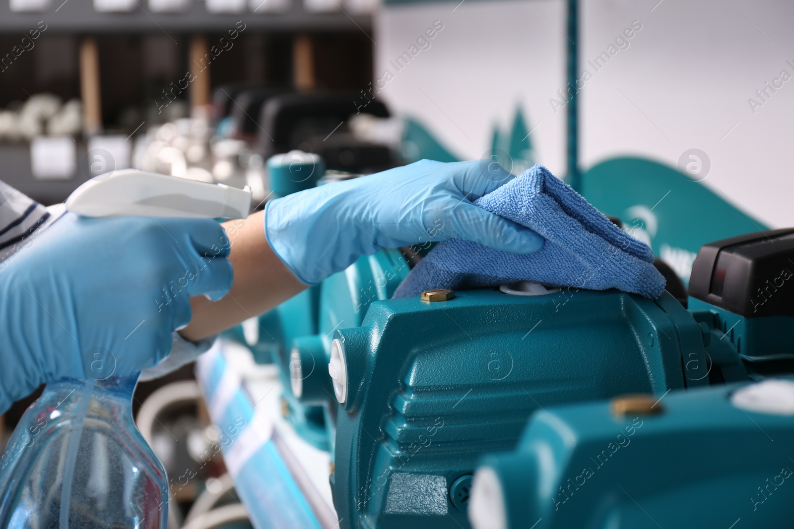 Photo of Woman cleaning water pump with rag and detergent in bathroom fixtures store, closeup