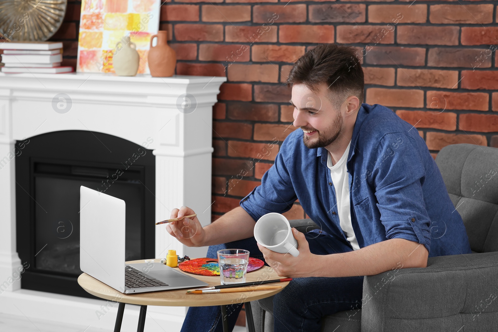 Photo of Man learning to decorate cup while watching online course at home. Time for hobby