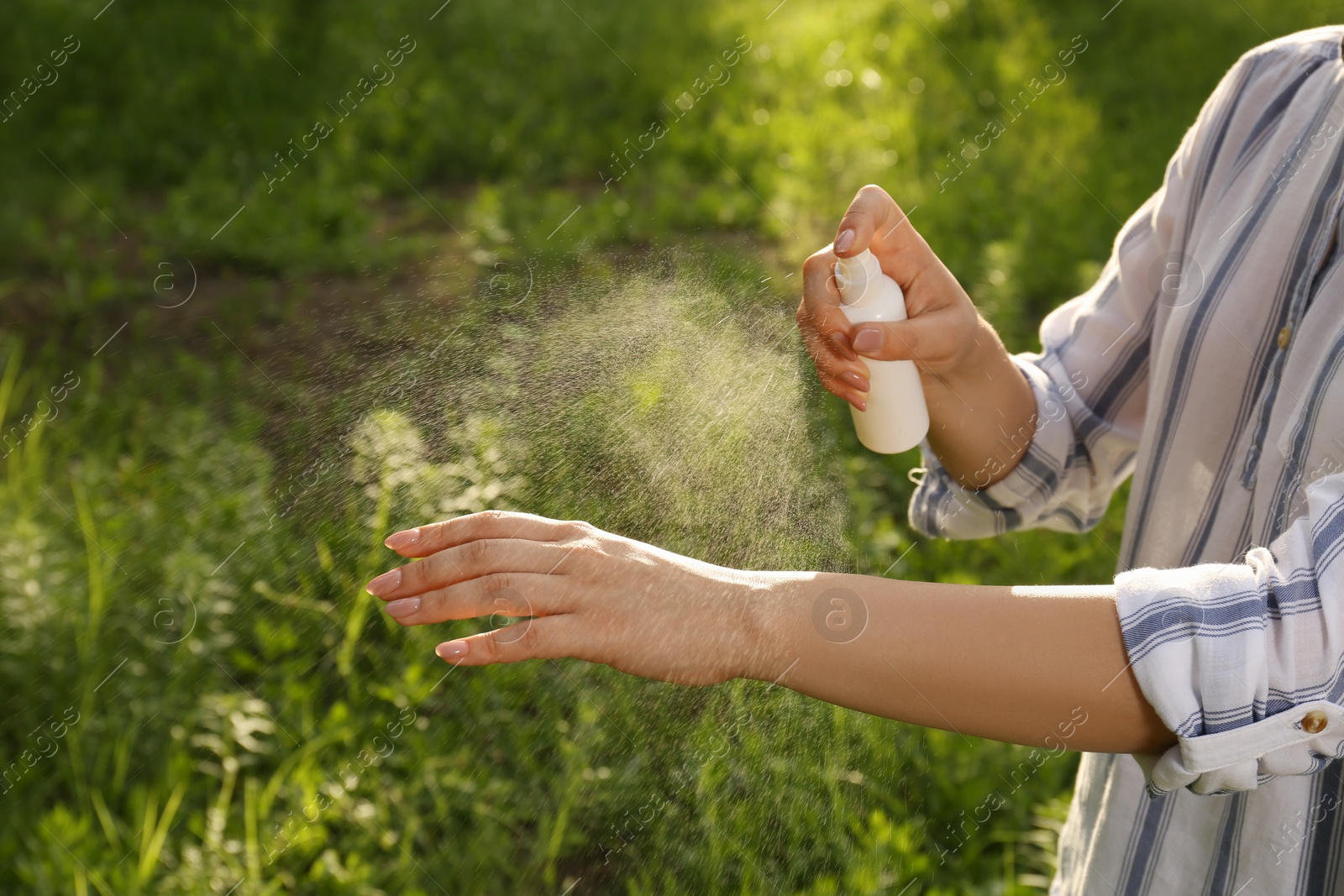 Photo of Woman applying insect repellent on hand in park, closeup. Tick bites prevention