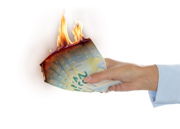 Image of Woman holding burning euro banknotes on white background, closeup