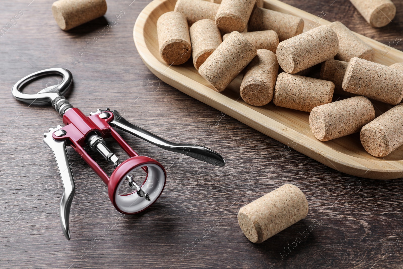 Photo of Corkscrew and wine bottle stoppers with plate on wooden table