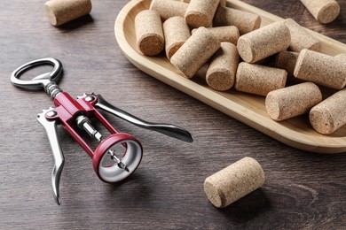 Photo of Corkscrew and wine bottle stoppers with plate on wooden table