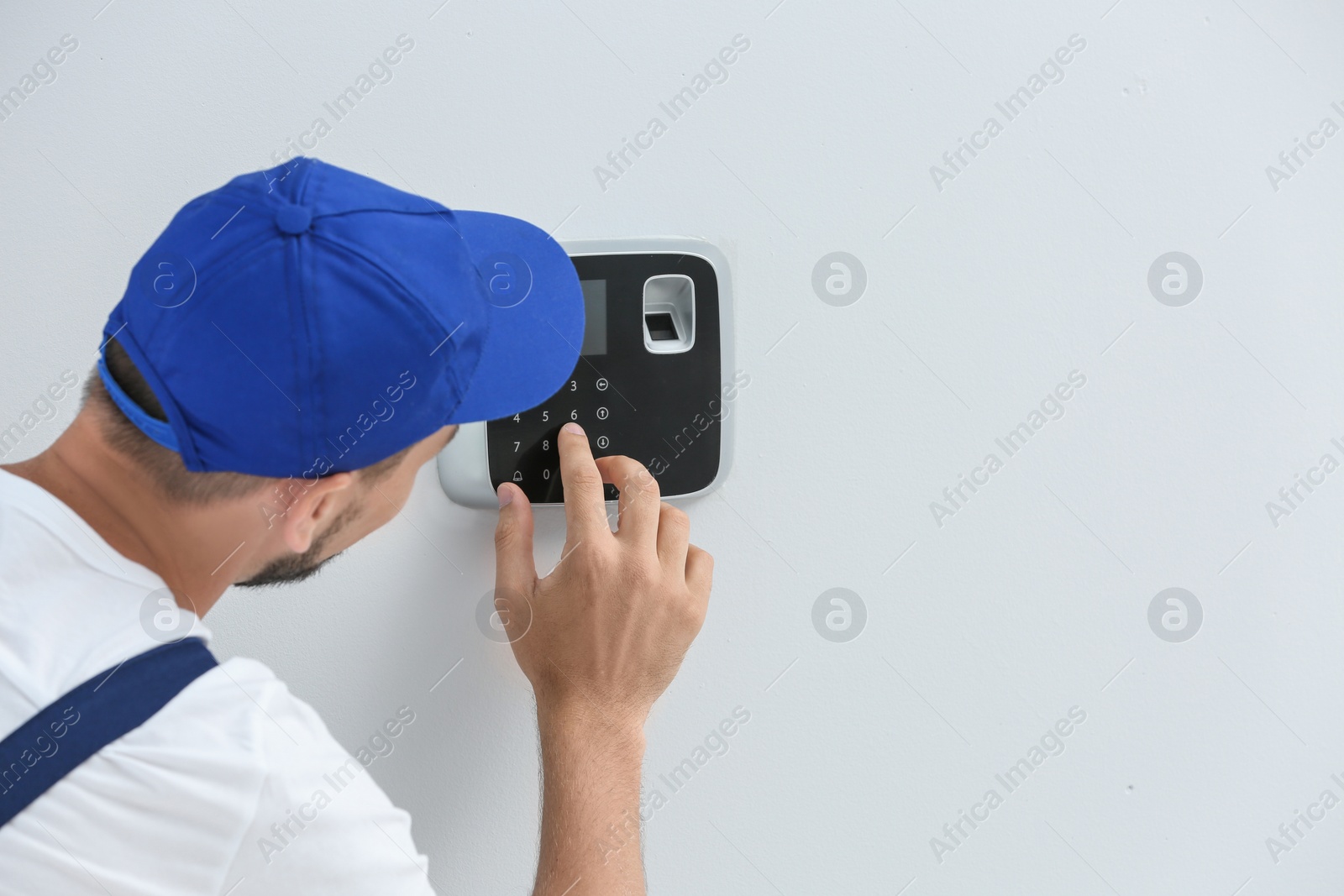 Photo of Young male technician programming alarm system indoors