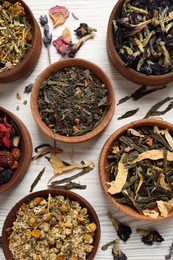 Flat lay composition with different dry teas on white wooden table