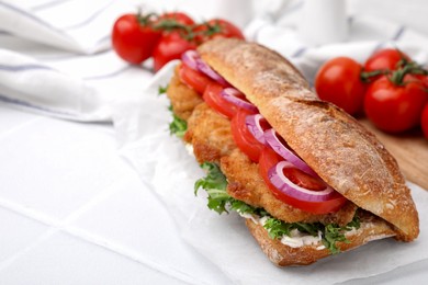 Photo of Delicious sandwich with schnitzel on white tiled table, closeup. Space for text