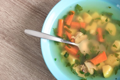 Photo of Bowl with delicious hot broth on table, top view. Cold treatment