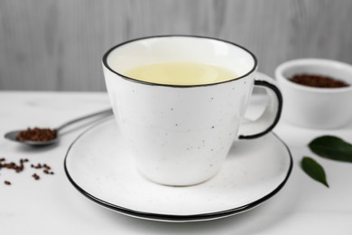 Photo of Cup of buckwheat tea on white marble table, closeup