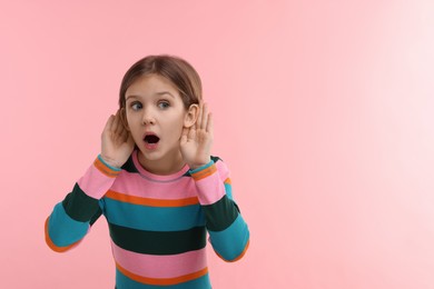Little girl with hearing problem on pink background, space for text