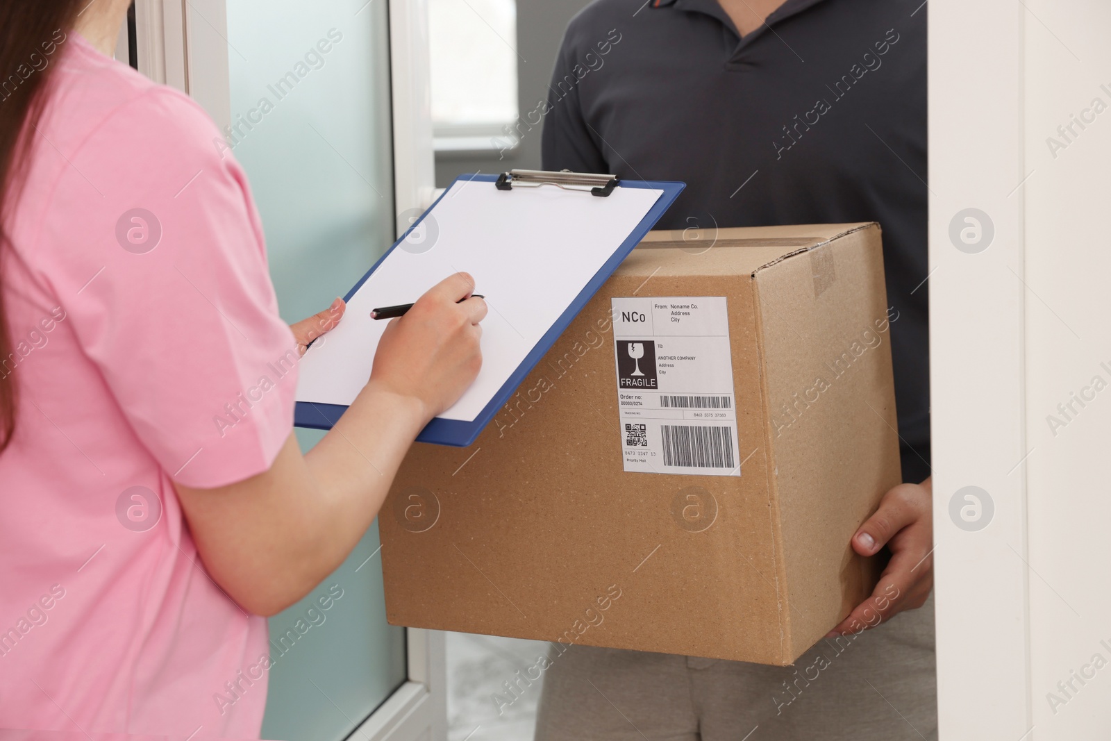 Photo of Woman signing for delivered parcel at home, closeup