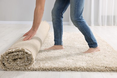 Man unrolling carpet on floor in room, closeup