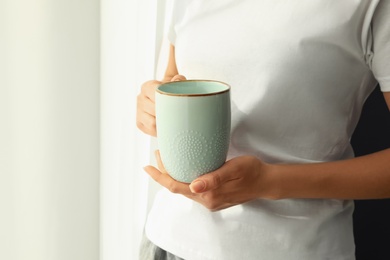 Woman with blue cup at home, closeup