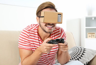 Young man using cardboard virtual reality headset at home