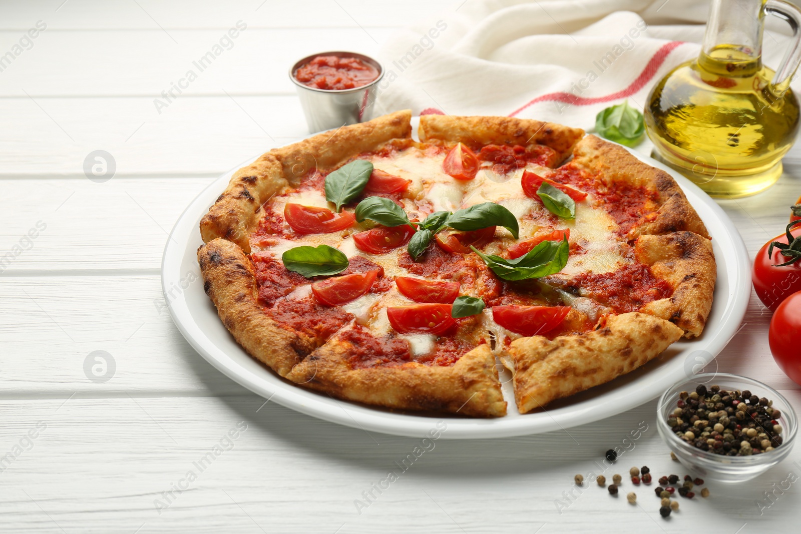 Photo of Delicious Margherita pizza and ingredients on white wooden table