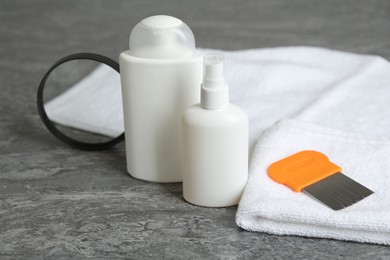 Photo of Cosmetic products, lice comb, magnifying glass and towel on grey table