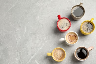 Many cups with different aromatic coffee on light grey marble table, flat lay. Space for text